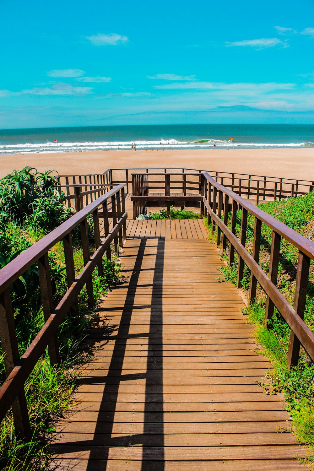 a wooden walkway leading to the beach on a sunny day