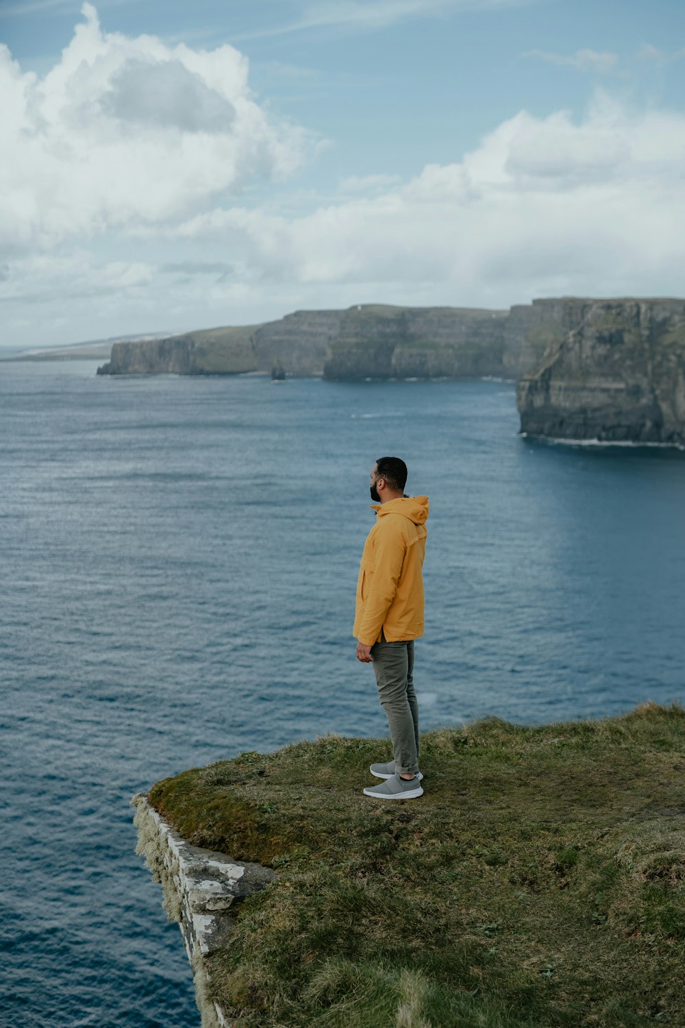 a man standing on top of a cliff near the ocean