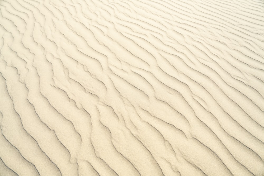 eine weiße Sanddüne mit Wellenlinien im Sand