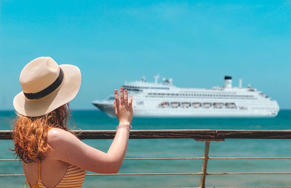 a woman in a yellow and white striped dress and hat is looking at a cruise