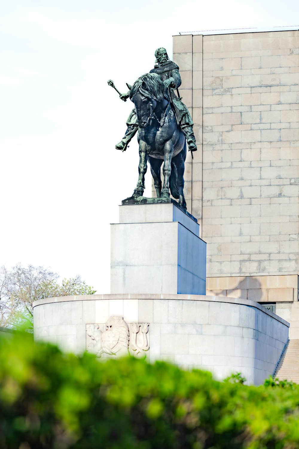 une statue d’un homme sur un cheval devant un bâtiment