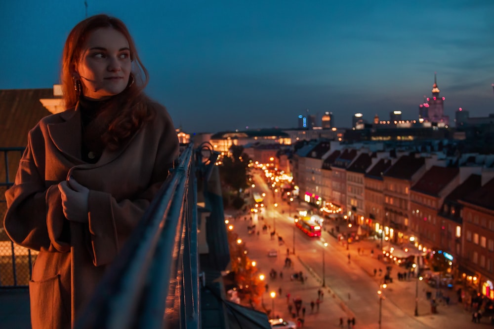 a woman standing on a balcony overlooking a city at night