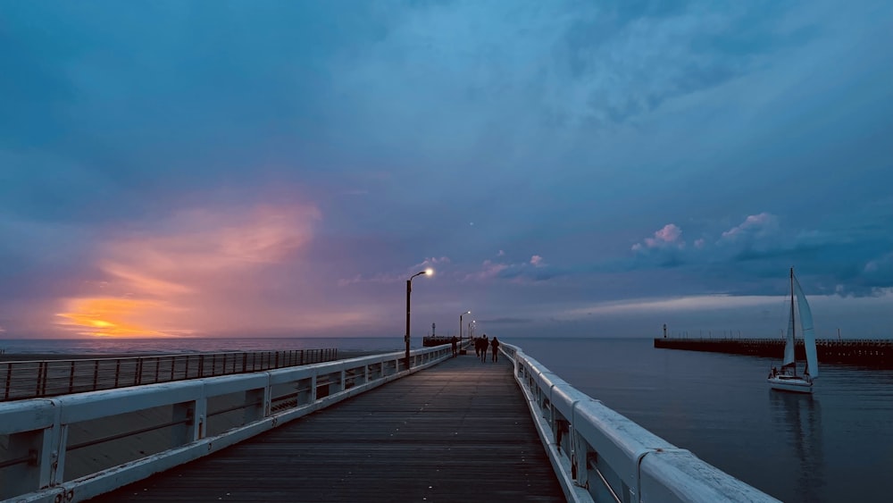 a pier with a light pole and sailboats in the water