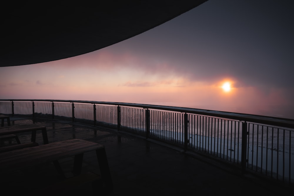 the sun is setting over the ocean from a balcony