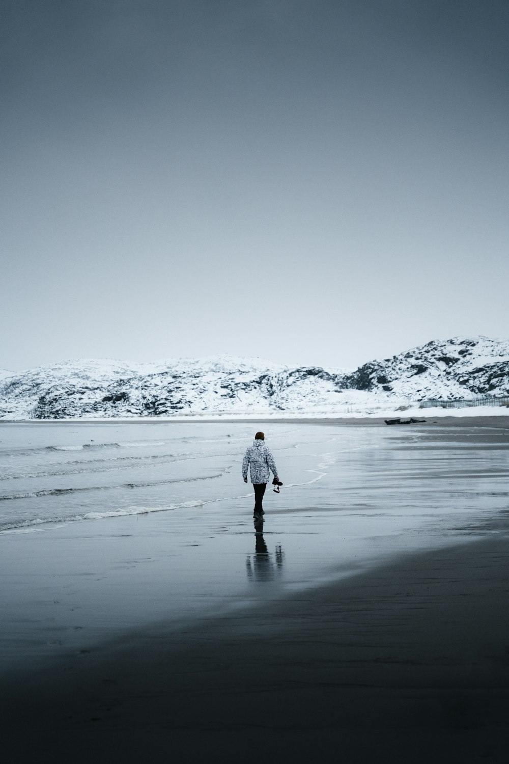 a person walking on a beach next to the ocean