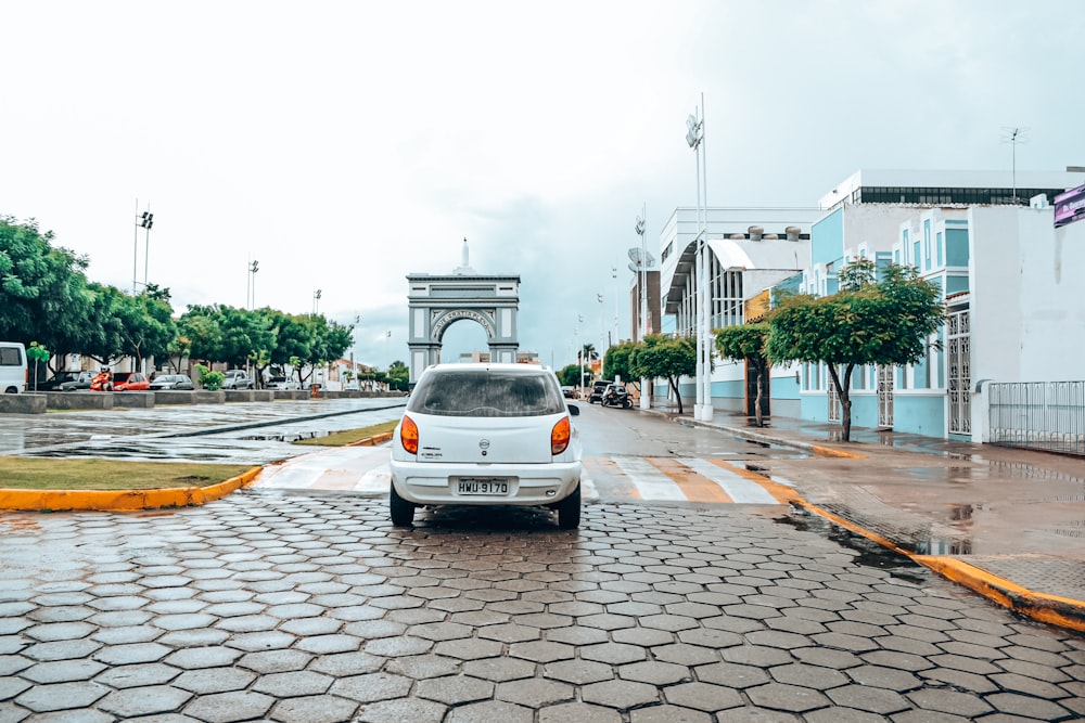 a white car driving down a wet street