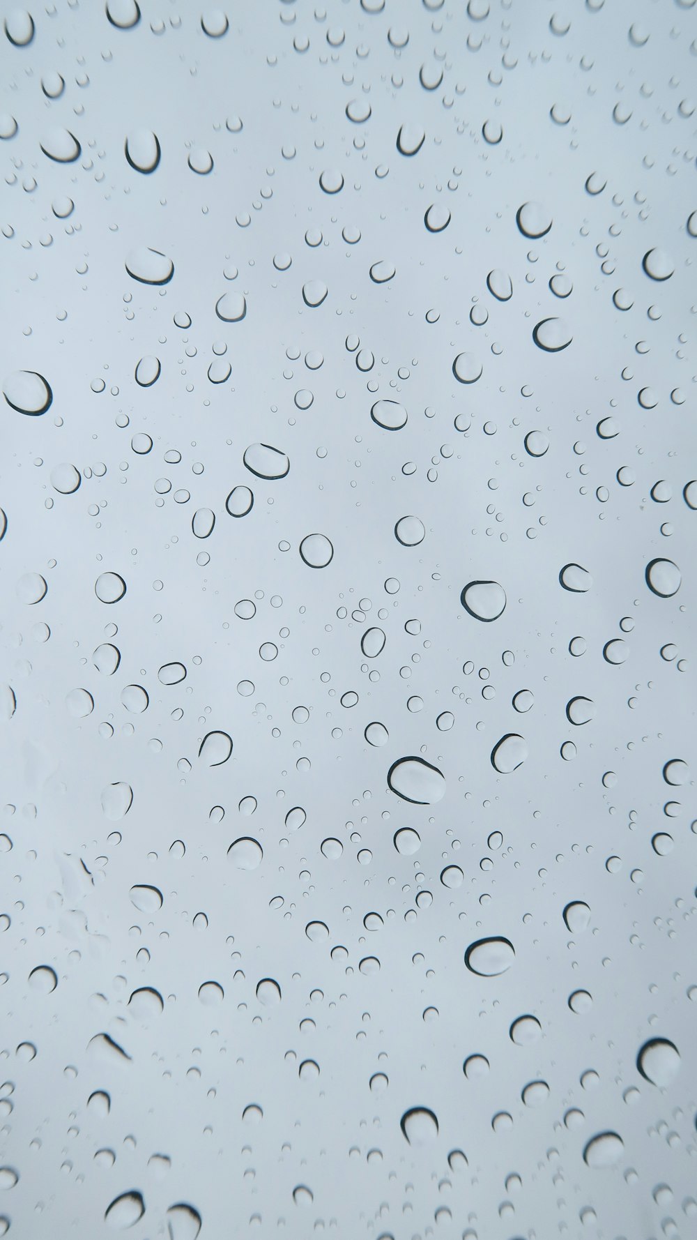 青空を背景に窓に落ちる雨粒