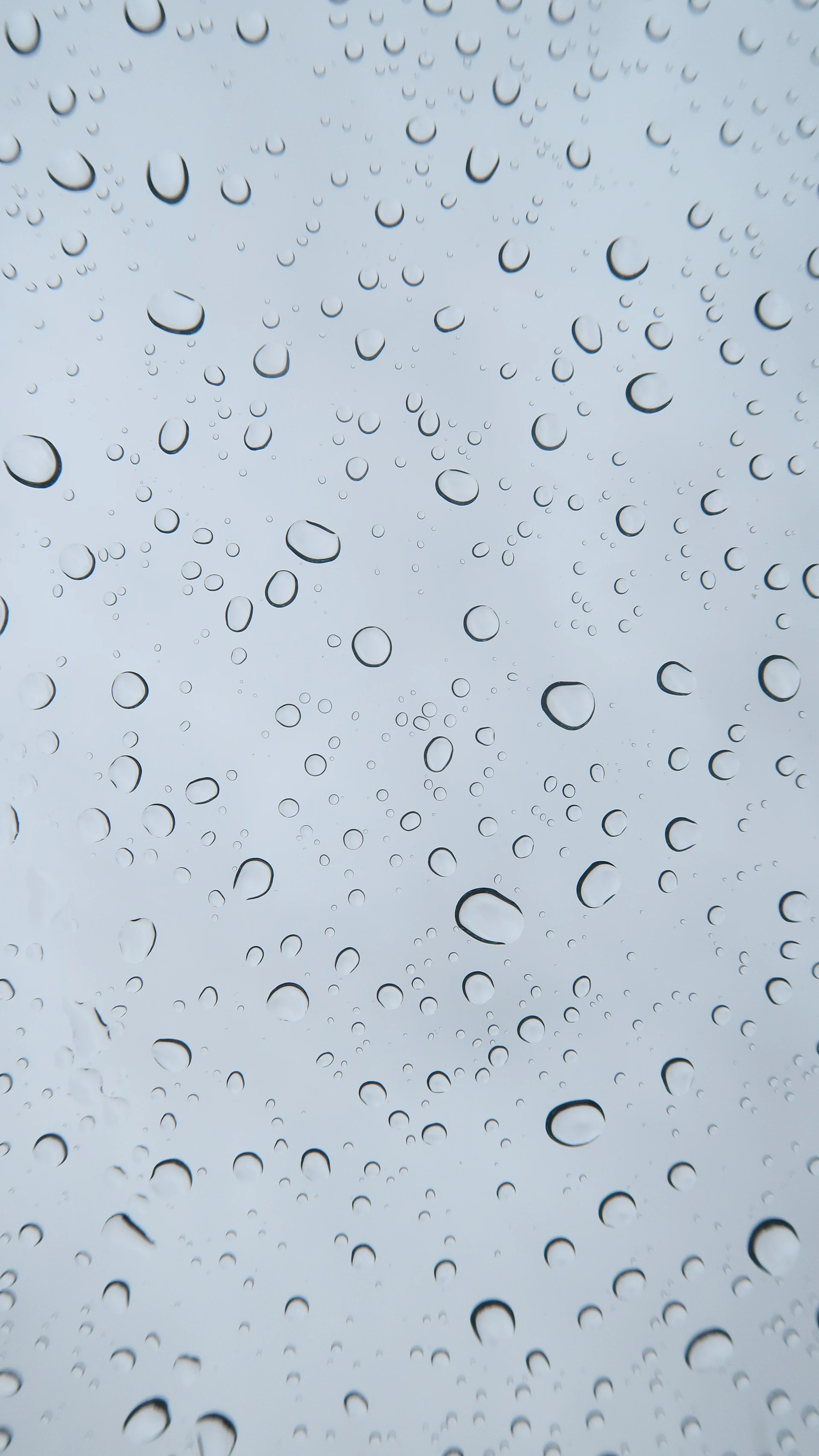 rain drops on a window with a blue sky in the background