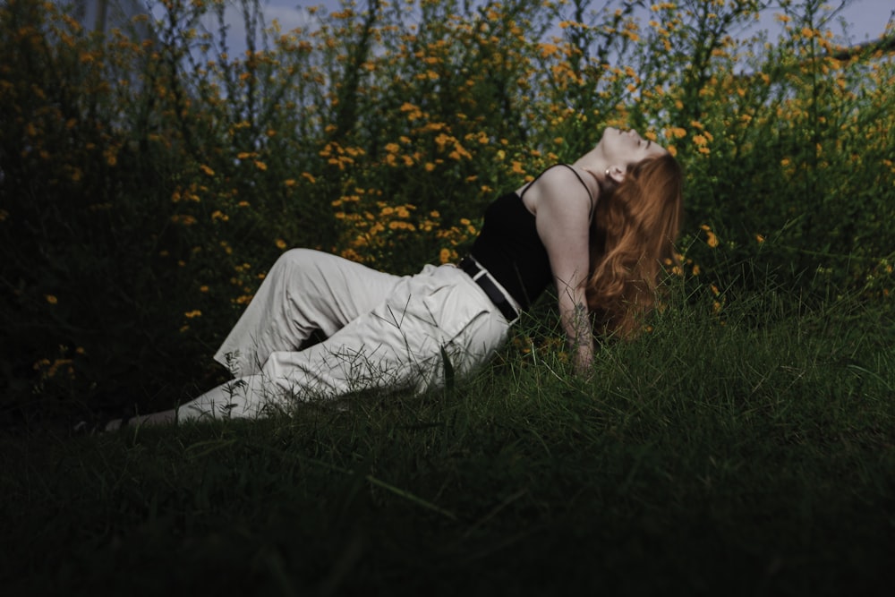 a woman laying on the ground in a field of flowers