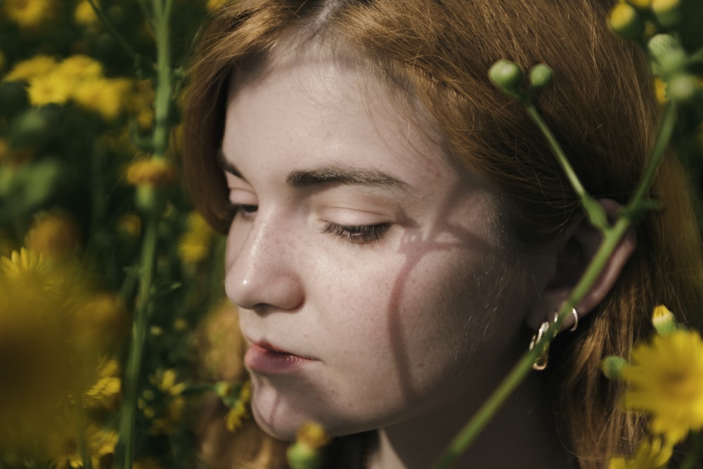 a woman with her eyes closed standing in a field of yellow flowers