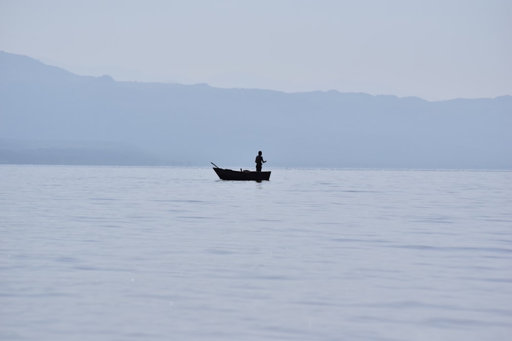 a man standing on a boat in the middle of the ocean