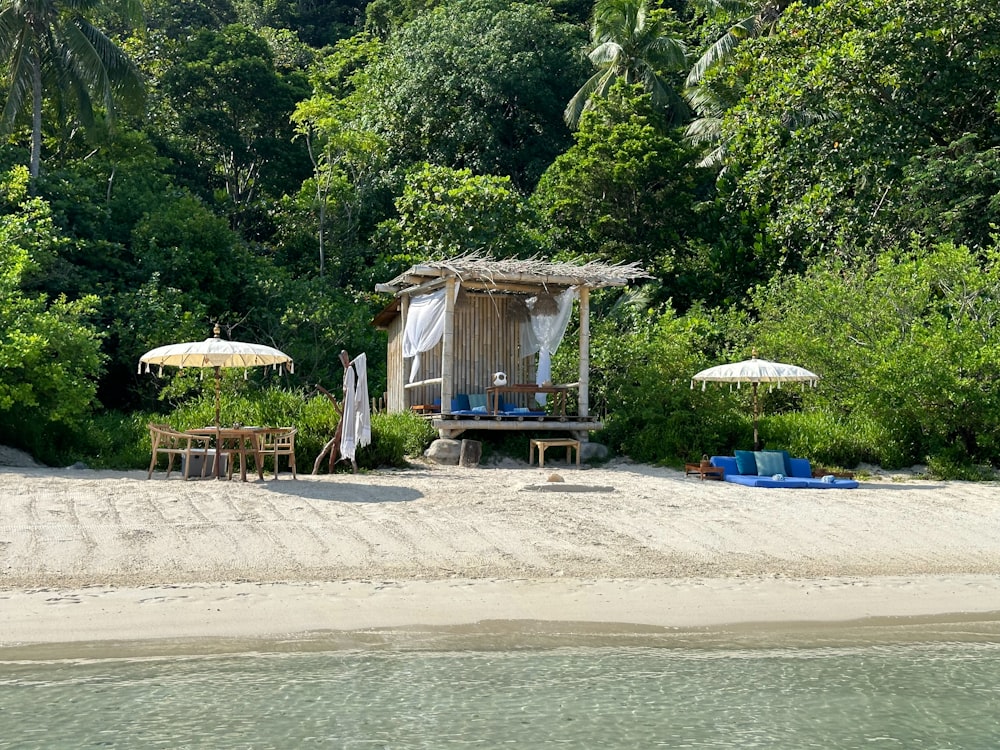 a small hut on a sandy beach next to the ocean