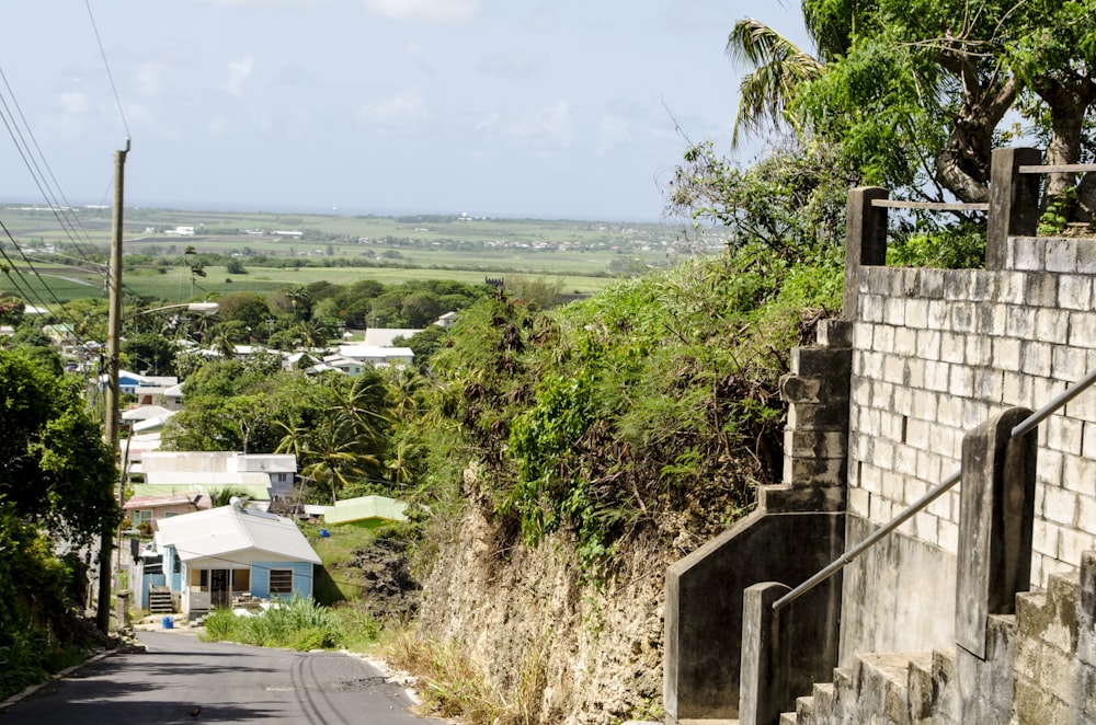 a street with a stone wall and a hill in the background