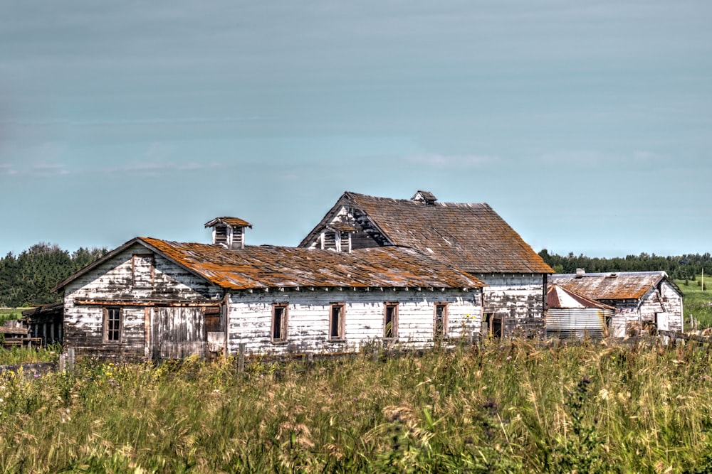 an old run down house in a field of tall grass