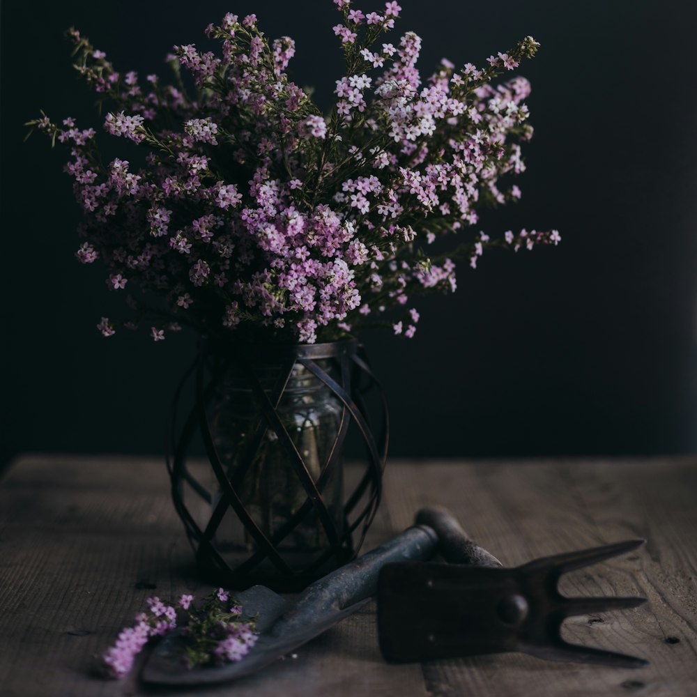 a vase filled with purple flowers next to a pair of wrenches