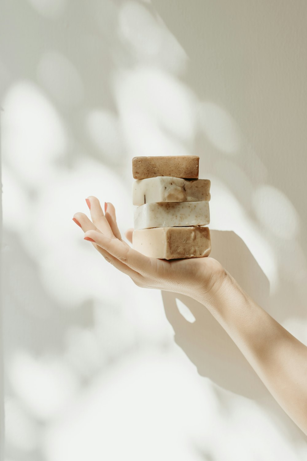 a woman's hand holding a stack of soap bars