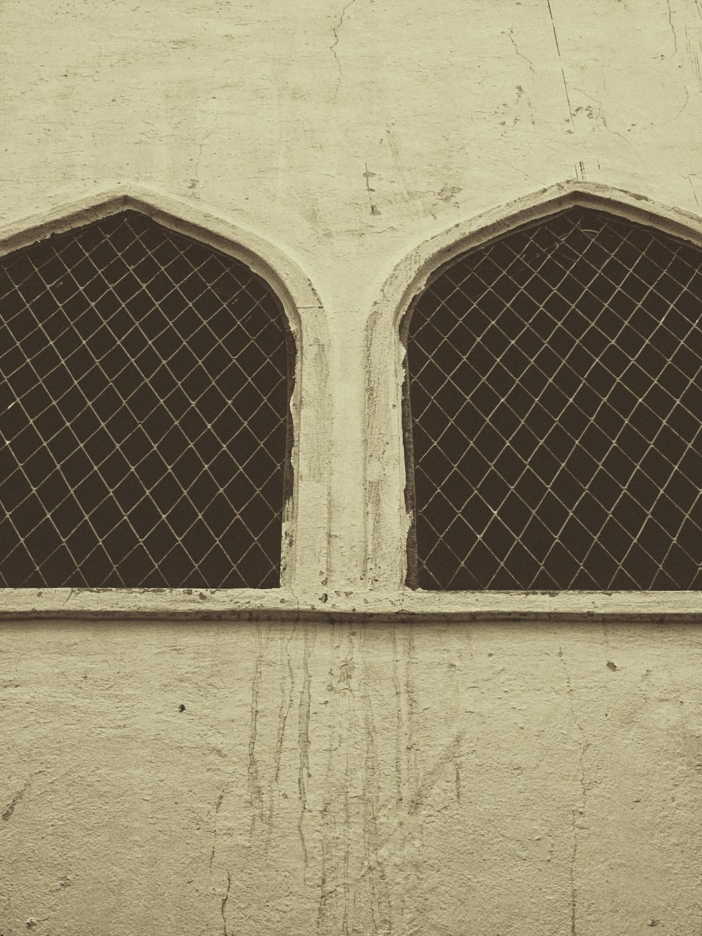 a window with two arched windows on the side of a building