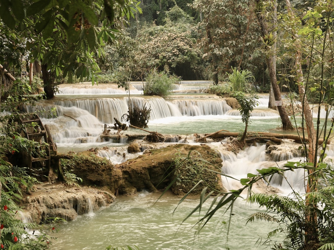 a small waterfall in the middle of a forest, Kuang Si Waterfall🇱🇦