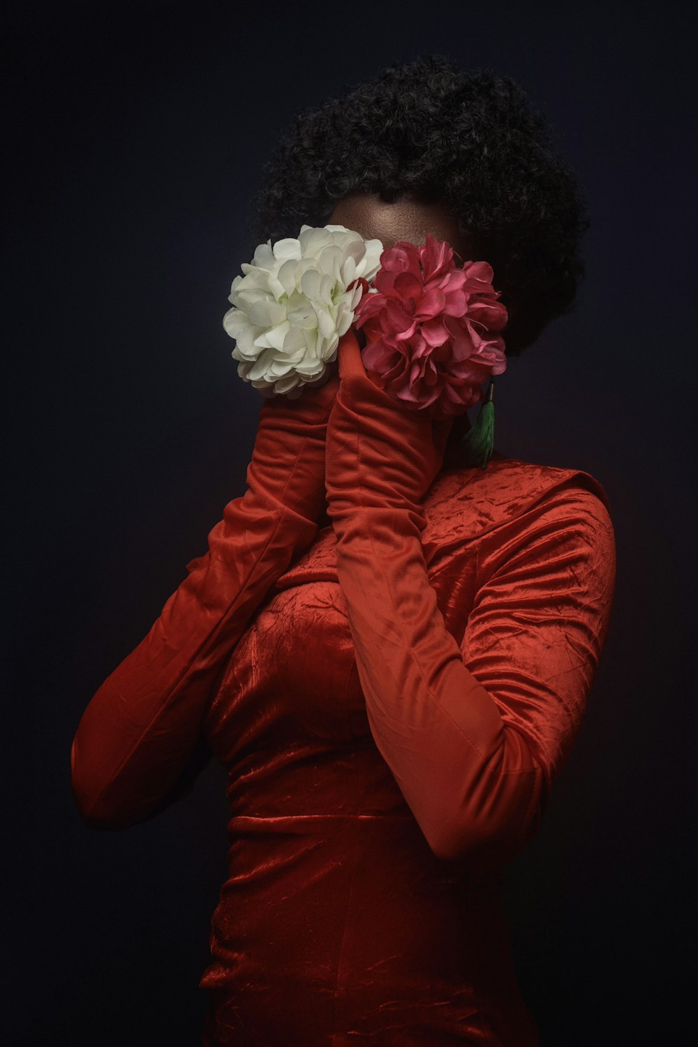 une femme en robe rouge tenant une fleur dans sa bouche