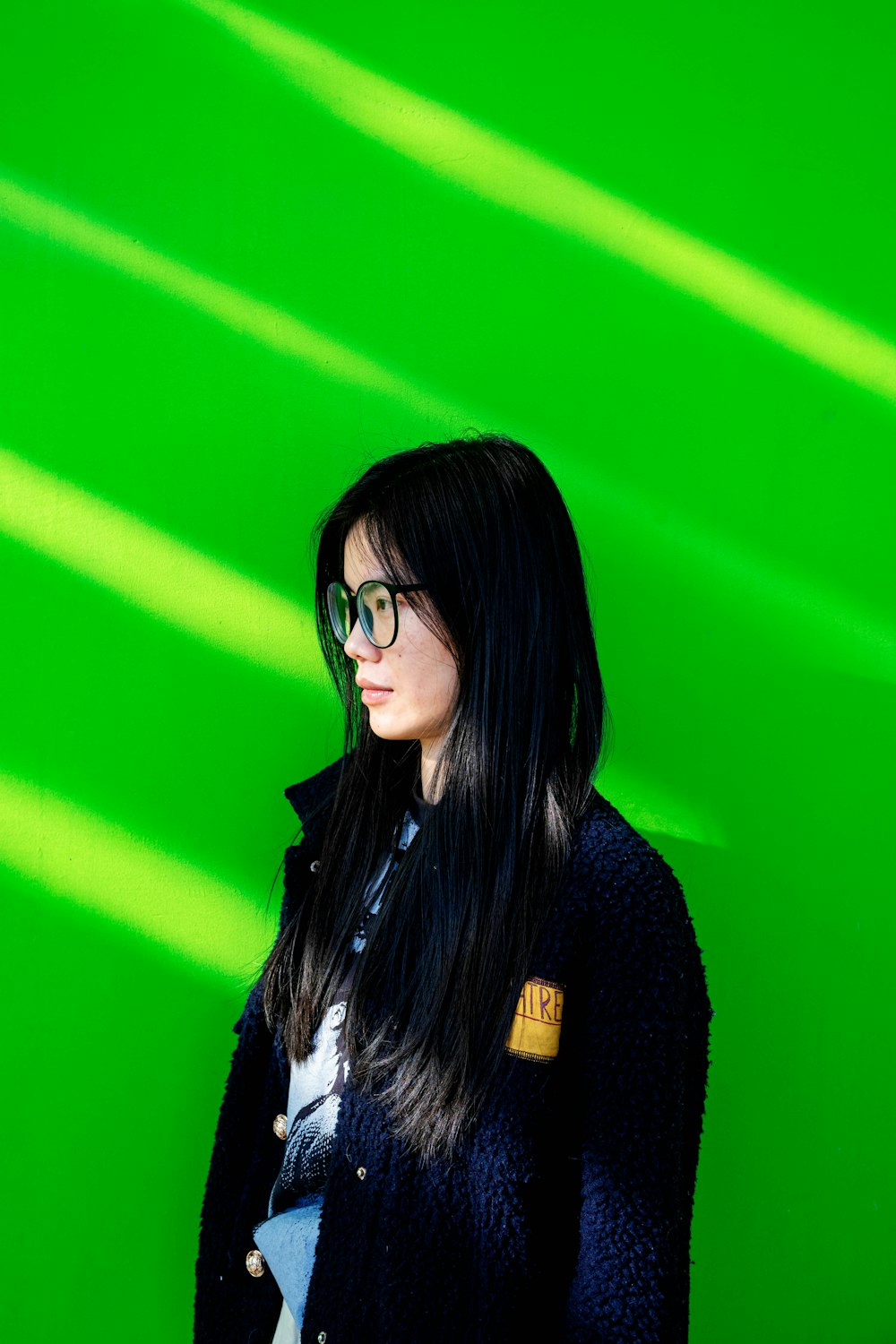 a woman wearing glasses standing in front of a green wall