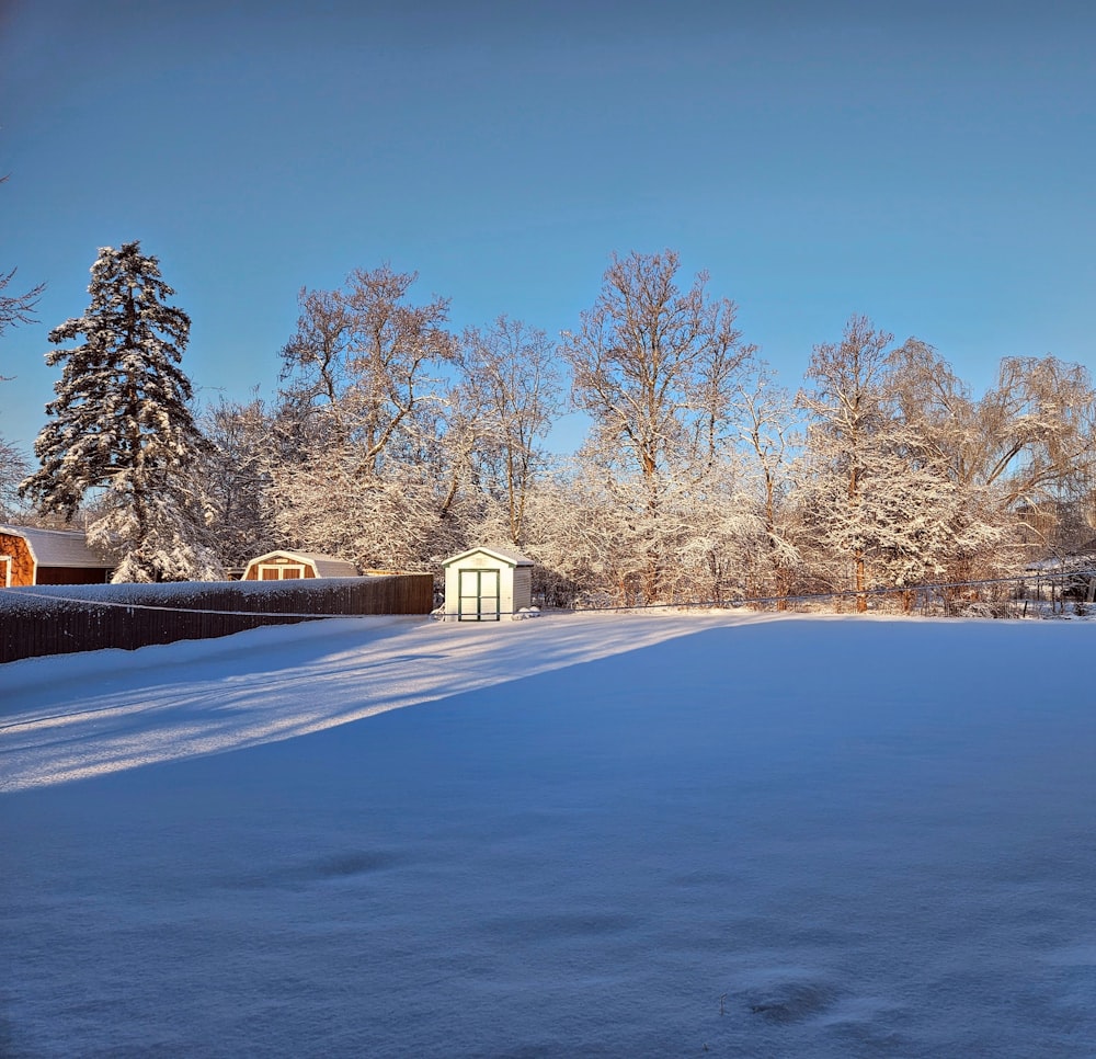 a snow covered field with a small building in the distance