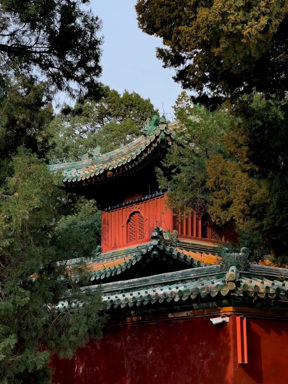 a red building with a green roof surrounded by trees