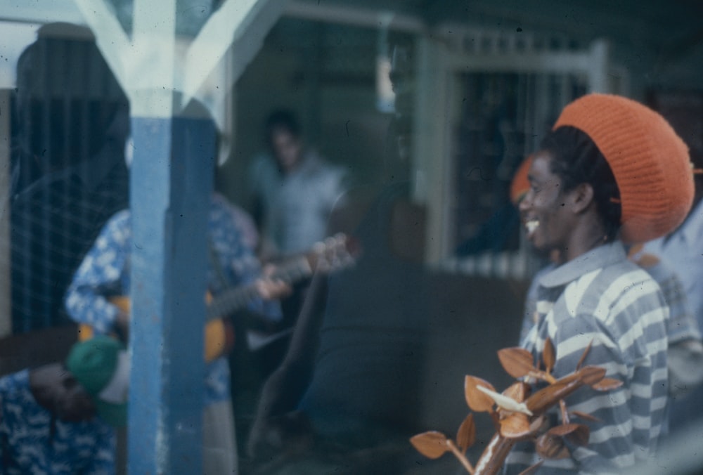 a man with an orange hat playing a guitar