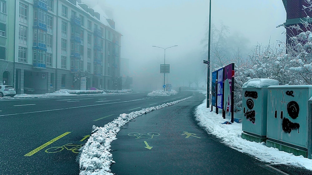 a street with snow on the ground and buildings in the background