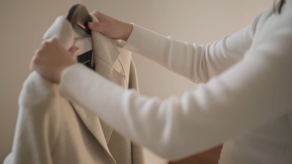 a woman is trying on a jacket with a tie