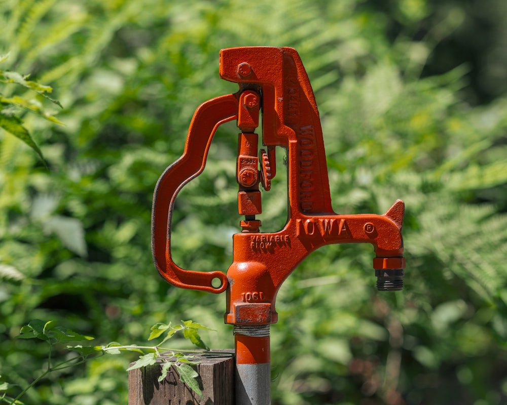 a close up of a red tool on a wooden post