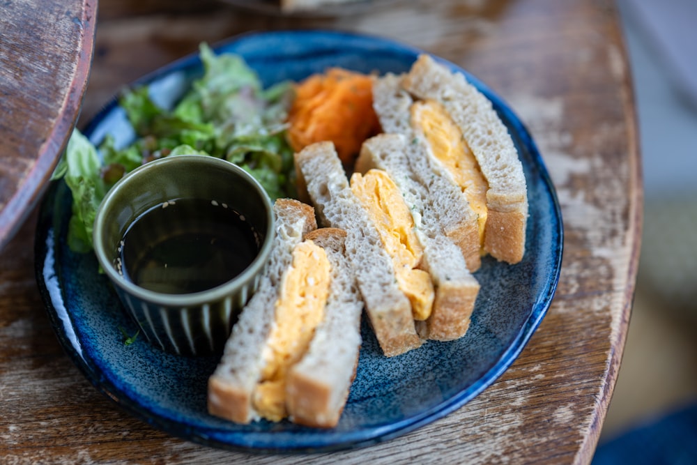 um prato azul coberto com sanduíches e uma salada