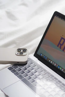 an open laptop computer sitting on top of a white bed