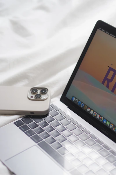 an open laptop computer sitting on top of a white bed