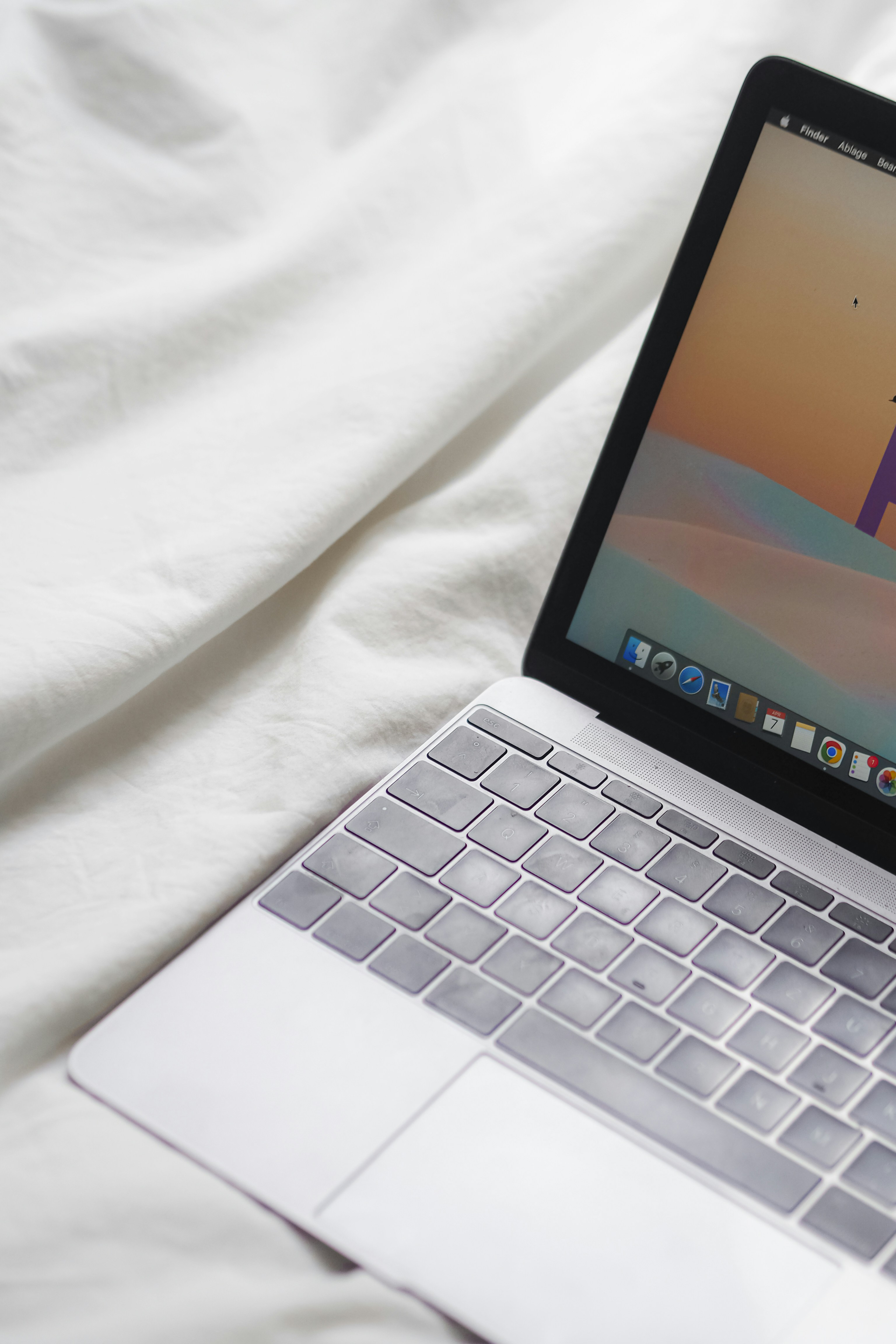 komputer laptop terbuka yang duduk di atas tempat tidur