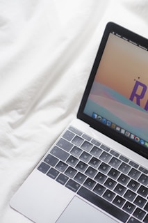 an open laptop computer sitting on top of a white bed