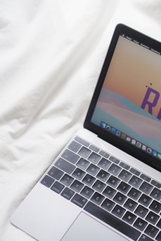 an open laptop computer sitting on top of a white bed
