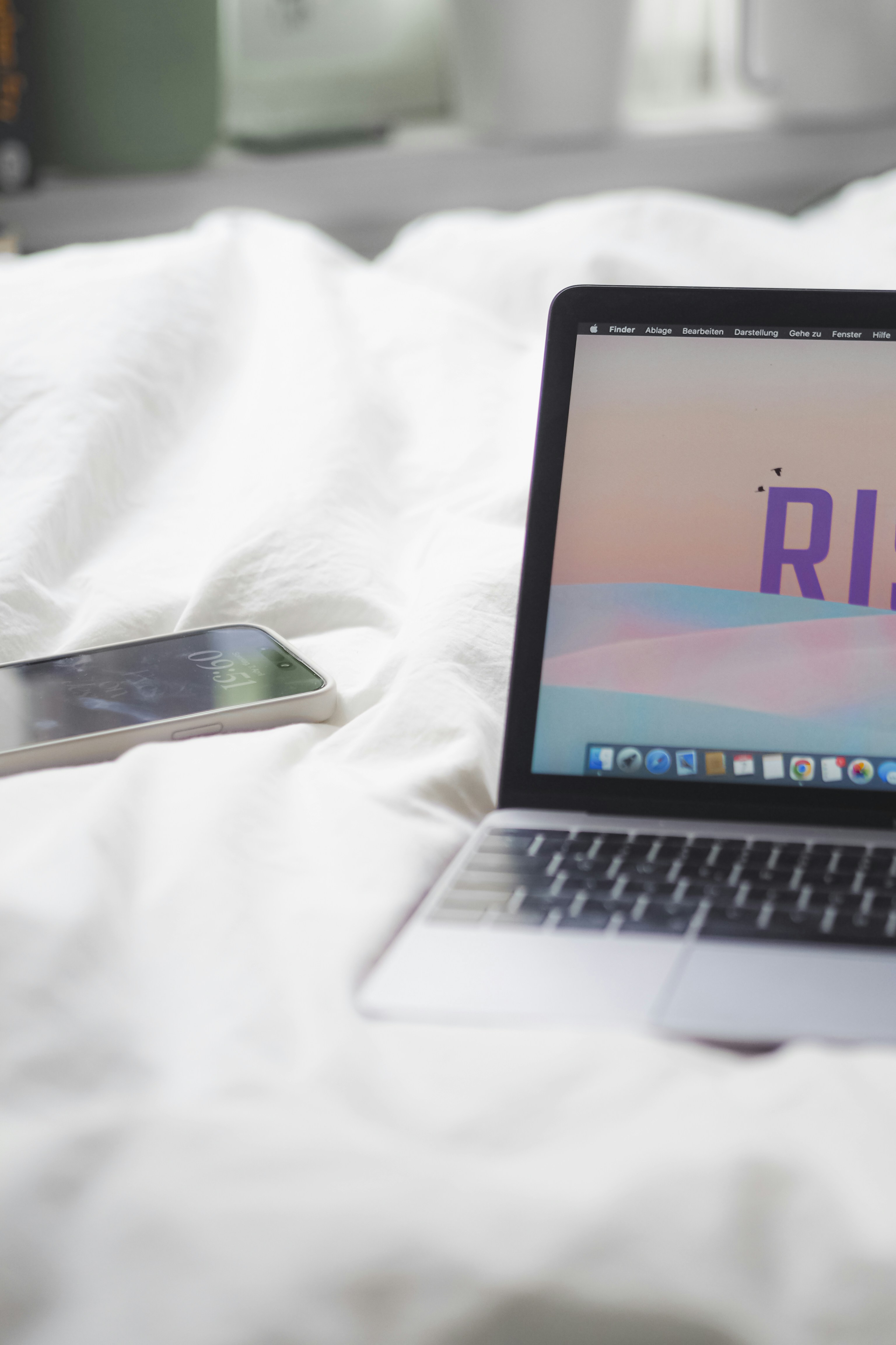 komputer laptop yang duduk di atas tempat tidur