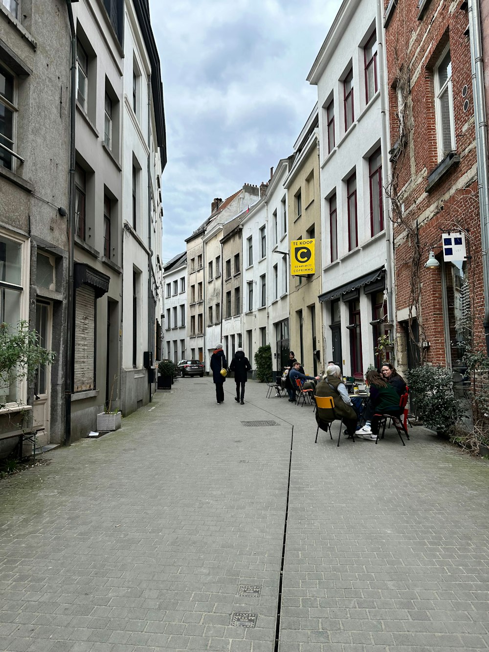 a group of people walking down a street next to tall buildings