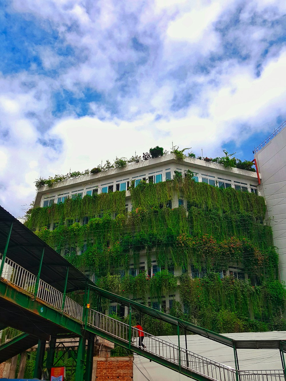 a building covered in green plants next to a staircase