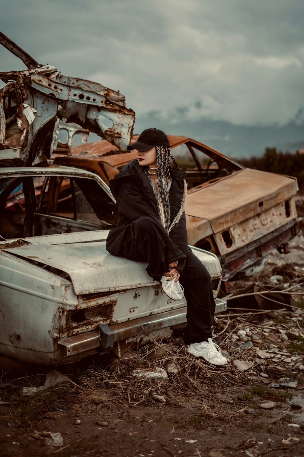 a man sitting on top of a car in a junk yard