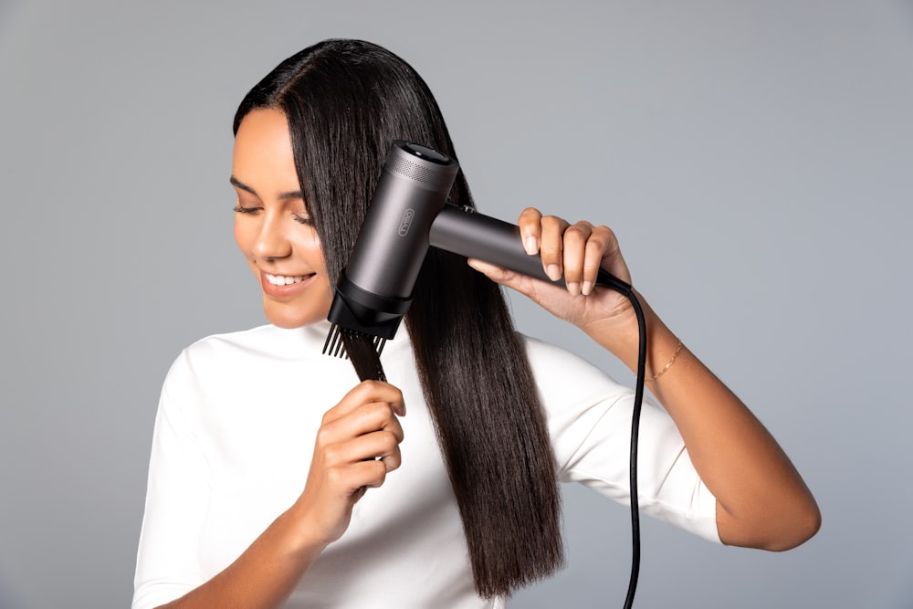 a woman blow drying her hair with a hair dryer