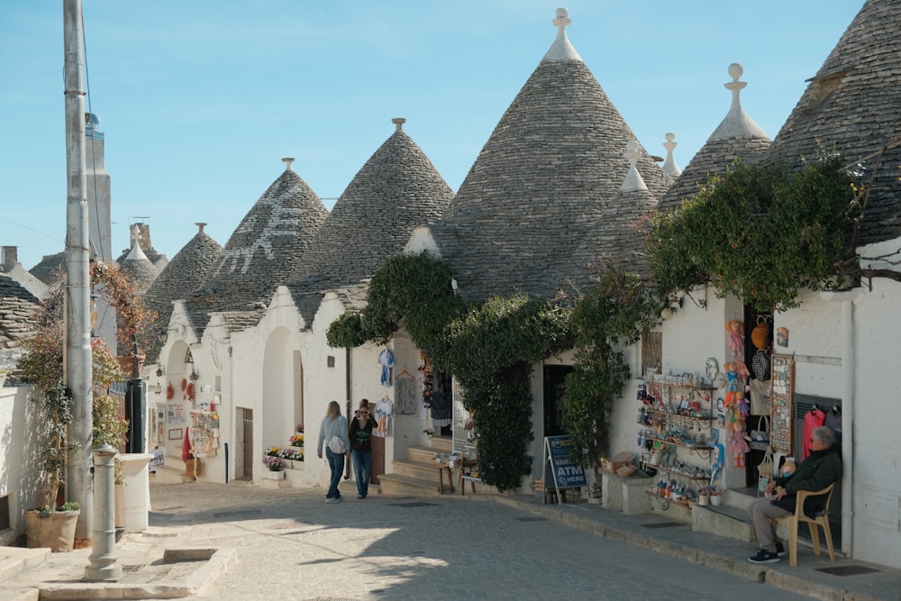 a group of people walking down a street next to white buildings