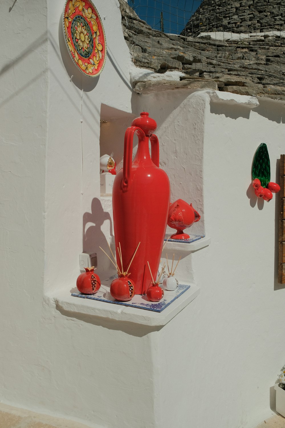 a red vase sitting on top of a window sill