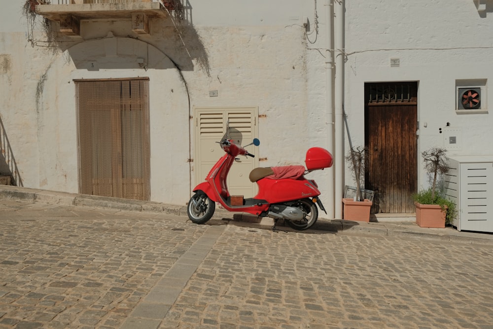a red scooter parked in front of a white building