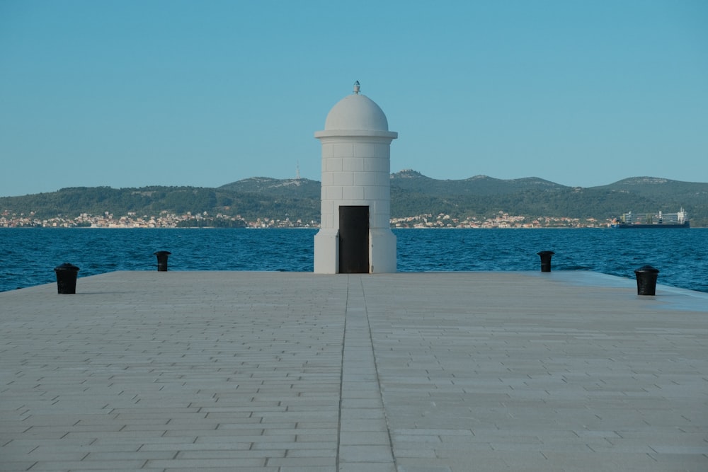 a white tower sitting on top of a pier next to a body of water