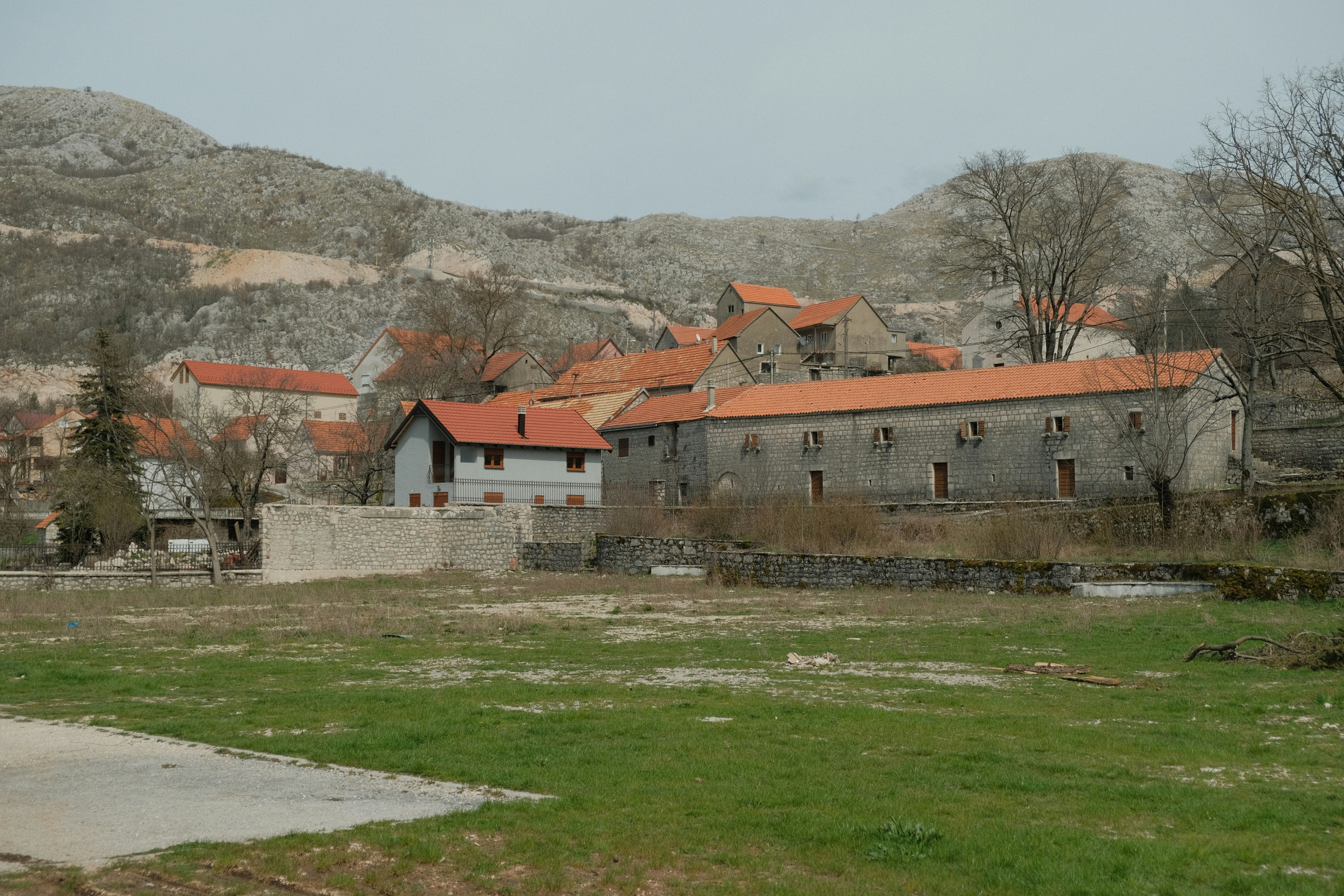 an old building with a red roof sits in the middle of a field