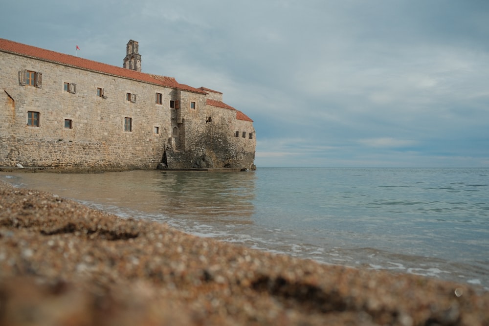 a stone building sitting on top of a beach next to the ocean