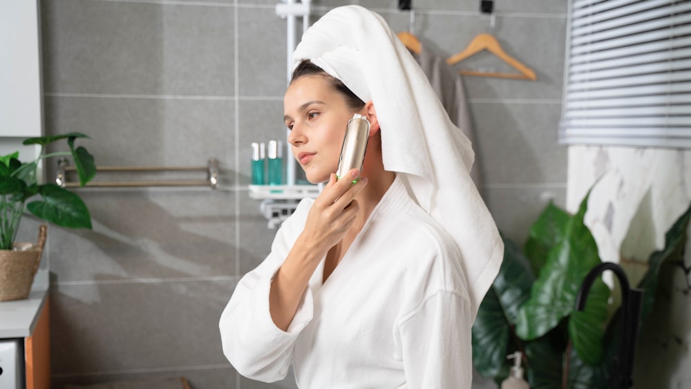 a woman with a towel on her head is looking at her cell phone