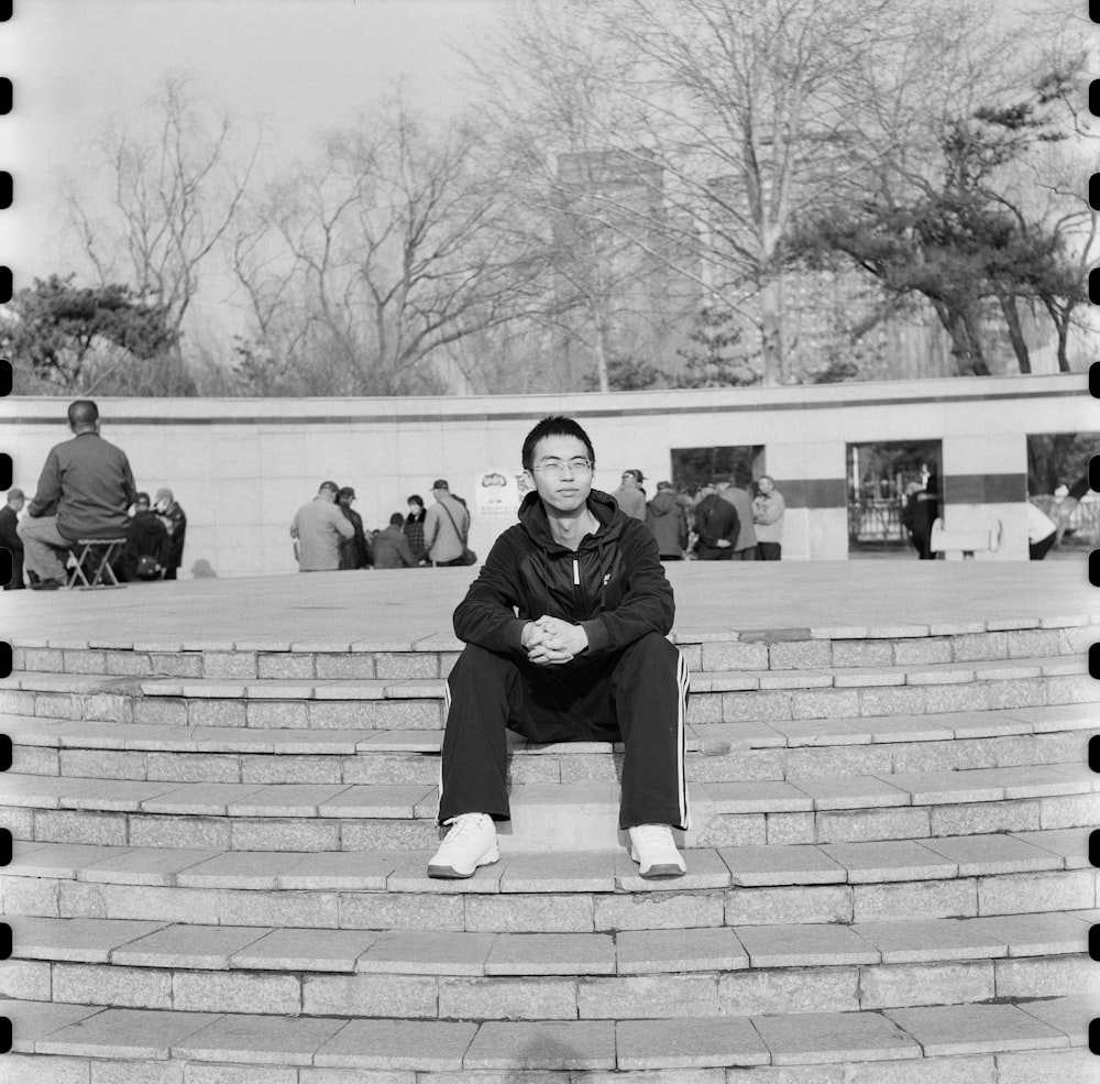 a black and white photo of a man sitting on steps