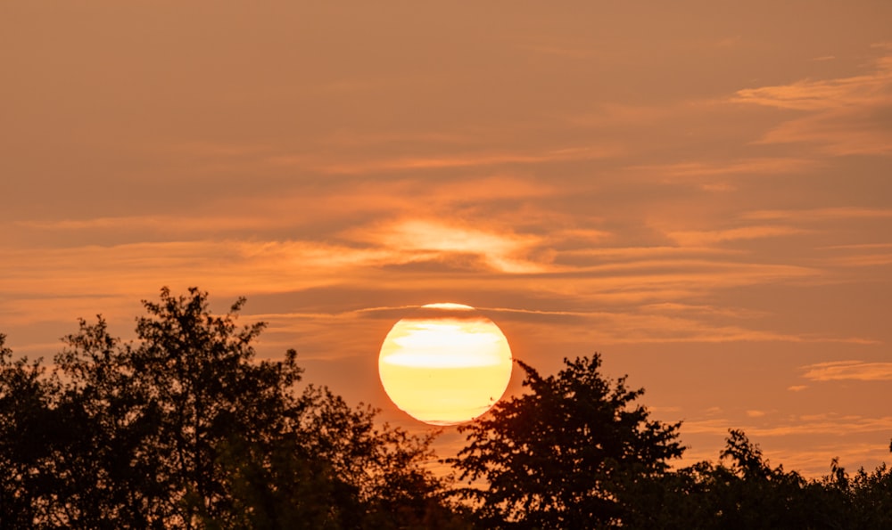 the sun is setting in the sky over the trees